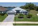 Lakefront home featuring well-manicured lawn, lovely landscaping, and long paver driveway at 3723 Belle Rose Dr, Leesburg, FL 34748