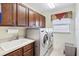 This spacious laundry room features a utility sink, wood cabinets, and a front loading washer and dryer at 3723 Belle Rose Dr, Leesburg, FL 34748