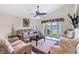Inviting living room features comfortable seating, ceiling fan, and serene lake views through large sliding doors at 3723 Belle Rose Dr, Leesburg, FL 34748