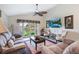 Well-lit living room boasts neutral tones, a ceiling fan, and picturesque views of the outside through sliding doors at 3723 Belle Rose Dr, Leesburg, FL 34748