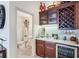 Elegant wet bar featuring custom wood cabinets, granite countertops, and wine cooler with powder room nearby at 3723 Belle Rose Dr, Leesburg, FL 34748