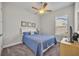 Cozy bedroom with carpet, a ceiling fan, a queen-size bed with blue bedding and nautical artwork at 4060 Longbow Dr, Clermont, FL 34711