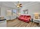 Bright living room with wood floors, large windows, a ceiling fan, and a comfortable red leather sofa at 4060 Longbow Dr, Clermont, FL 34711