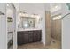 Bathroom with dual sink vanity, walk-in shower with tan tiling, and modern fixtures at 4972 Big Cypress St, Oxford, FL 34484