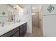 Bathroom with dual sink vanity, walk-in shower with tan tiling, and bright lighting at 4972 Big Cypress St, Oxford, FL 34484