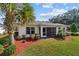 Home's exterior featuring a porch, white walls, green grass, red mulch and a palm tree at 4972 Big Cypress St, Oxford, FL 34484
