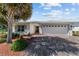 Inviting single-story home with landscaped yard, brick-paved driveway, and a two-car garage at 4972 Big Cypress St, Oxford, FL 34484