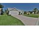 Charming home featuring a well-manicured lawn, brick accents, neutral siding, and a paved driveway leading to a two-car garage at 631 San Pedro Dr, The Villages, FL 32159