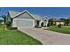 Charming home featuring a paved driveway leading to a two-car garage, neutral siding, brick accents, and manicured lawn at 631 San Pedro Dr, The Villages, FL 32159