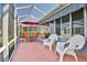 View of the screened patio featuring outdoor table, chairs, umbrella, and white resin chairs at 631 San Pedro Dr, The Villages, FL 32159