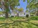 Single-story home with mature trees, lawn, and window awnings for added character at 715 Megan Circle, The Villages, FL 32159