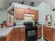 View of the kitchen with black stove, wood cabinets, and neutral countertops at 7260 Se 124Th Ln, Belleview, FL 34420