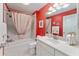 Bright bathroom featuring a shower-over-tub, white vanity and sink, and a striking red accent wall at 760 Hammond Pl, The Villages, FL 32162