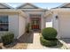 Charming home entrance with a symmetrical walkway, decorative shrubs, and a wooden front door at 760 Hammond Pl, The Villages, FL 32162