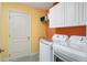 Brightly painted laundry room features modern washer and dryer, white cabinets and access door at 760 Hammond Pl, The Villages, FL 32162