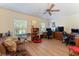 Cozy living room with two work stations, a ceiling fan, hardwood floors, and lots of natural light at 760 Hammond Pl, The Villages, FL 32162