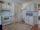 Compact kitchen with light wood cabinets, classic appliances, and patterned wallpaper at 819 Hibiscus Dr, The Villages, FL 32159