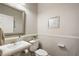 Well-lit powder room featuring a pedestal sink, decorative mirror, and elegant wainscoting at 848 Hawk Lndg, Fruitland Park, FL 34731
