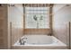 Inviting bathtub beneath a decorative glass block window, perfect for relaxation at 848 Hawk Lndg, Fruitland Park, FL 34731