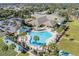 Aerial view of a resort-style community pool with palm trees, lounge chairs, and nearby clubhouse at 9593 Se 124Th Loop, Summerfield, FL 34491