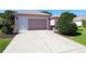 Spacious driveway leading to a charming home with an attached garage and mature landscaping at 9593 Se 124Th Loop, Summerfield, FL 34491