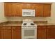 Kitchen area with oak cabinets and white stove and microwave at 9593 Se 124Th Loop, Summerfield, FL 34491
