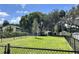 Expansive grassy community area featuring mature trees and a covered seating area, all enclosed by a secure black chain-link fence at 12129 Grand Oak Ln, Oxford, FL 34484