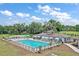 Community pool featuring several lounge chairs and umbrellas surrounded by mature trees at 12129 Grand Oak Ln, Oxford, FL 34484
