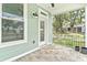 Covered porch with durable stone tile, calming green walls, and inviting view of the yard at 12129 Grand Oak Ln, Oxford, FL 34484