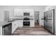 Well-lit kitchen with stainless steel appliances, white cabinets, and wood-look flooring at 16374 Se 88Th Ave, Summerfield, FL 34491