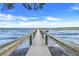Picturesque wooden dock with metal railing over blue water and a partly cloudy sky at 16538 Rockwell Heights Ln, Clermont, FL 34711