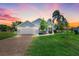 Beautiful home with lush lawn, brick driveway, palm trees, and inviting front porch at twilight at 16538 Rockwell Heights Ln, Clermont, FL 34711