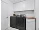 This laundry room features modern washer and dryer units, complemented by white cabinets at 16538 Rockwell Heights Ln, Clermont, FL 34711