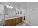 Bathroom with a large mirror, double sinks, wooden cabinets, and stylish tile flooring at 1743 Landrum Ln, The Villages, FL 32162