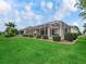 Expansive backyard featuring a screened lanai, manicured lawn, and meticulously maintained landscaping at 17930 Se 87Th Bourne Ave, The Villages, FL 32162
