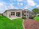 Well-maintained backyard featuring a screened-in lanai, lush green grass, and a neatly landscaped perimeter at 17930 Se 87Th Bourne Ave, The Villages, FL 32162