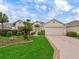 Charming single-story home featuring a meticulously landscaped yard, beige stucco, and a spacious two-car garage at 17930 Se 87Th Bourne Ave, The Villages, FL 32162