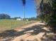 Scenic dirt road surrounded by trees and a fenced, green field under a sunny sky at 19726 Mccall Rd, Altoona, FL 32702