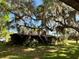 Cozy home exterior partially obscured by a grand, moss-draped tree, showcasing a tranquil, shaded setting at 19726 Mccall Rd, Altoona, FL 32702