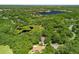 Aerial view of a lush, wooded community with a large lake and a home with a brown roof nestled among trees at 2010 Otters Pond Rd, Fruitland Park, FL 34731