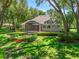 Backyard features a screened-in porch, landscaped patio, lush green lawn, and mature trees, ideal for outdoor living at 2010 Otters Pond Rd, Fruitland Park, FL 34731