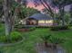 Charming home exterior featuring a screened-in porch, landscaped yard, and mature trees at dusk at 2010 Otters Pond Rd, Fruitland Park, FL 34731
