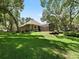 Expansive, well-maintained lawn with the home's exterior, screened lanai and mature trees in the background at 2010 Otters Pond Rd, Fruitland Park, FL 34731