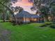 Spacious home exterior with a screened-in patio, lush landscaping, and beautiful sunset lighting at 2010 Otters Pond Rd, Fruitland Park, FL 34731