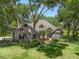 Charming single-story home featuring a stone facade, well-manicured lawn, mature trees, and inviting entrance at 2010 Otters Pond Rd, Fruitland Park, FL 34731