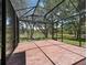 Enclosed lanai features brick flooring and screened walls, offering views of the lush green yard and pond beyond at 2010 Otters Pond Rd, Fruitland Park, FL 34731