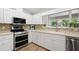 Well-lit kitchen with stainless steel appliances, white cabinetry, and a beige tiled backsplash at 2420 Sr 471, Sumterville, FL 33585