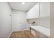 Bright laundry room featuring white cabinets, folding counter, and wood-look tile floors at 2420 Sr 471, Sumterville, FL 33585