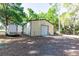 Outbuilding with a garage door and trailer on a gravel yard, surrounded by lush trees at 2420 Sr 471, Sumterville, FL 33585