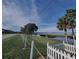 Scenic street view showcasing lush greenery, lake views, and charming white picket fences under a clear blue sky at 292 Nautica Mile Dr, Clermont, FL 34711